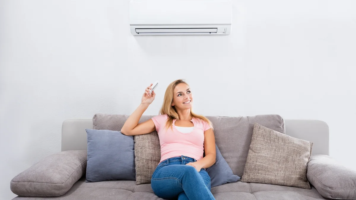 Moradora controlando o ar-condicionado instalado na sala